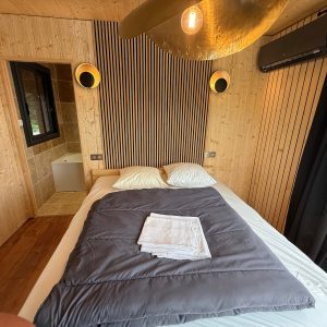 Chalet moderne en bois, avec lit douillet et décoration épurée, ambiance chaleureuse.