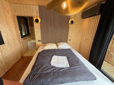 Chalet moderne en bois, avec lit douillet et décoration épurée, ambiance chaleureuse.