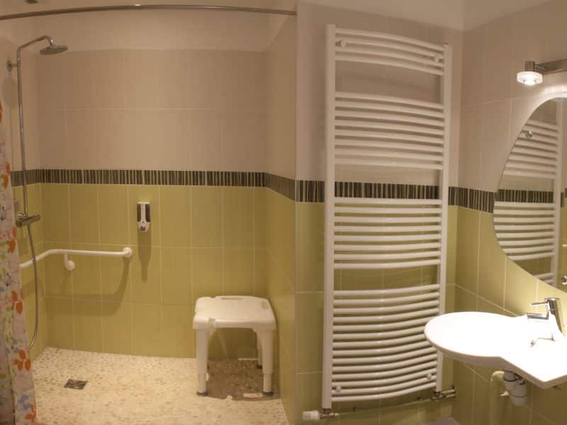 Salle de bain dun hébergement touristique, avec douche spacieuse et carrelage coloré.