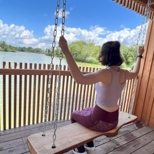 Hébergement insolite : une cabane en bois avec une balançoire surplombant un lac paisible.