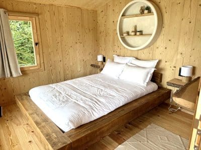 Chalet en bois chaleureux avec lit douillet, décor minimaliste et lumière naturelle.