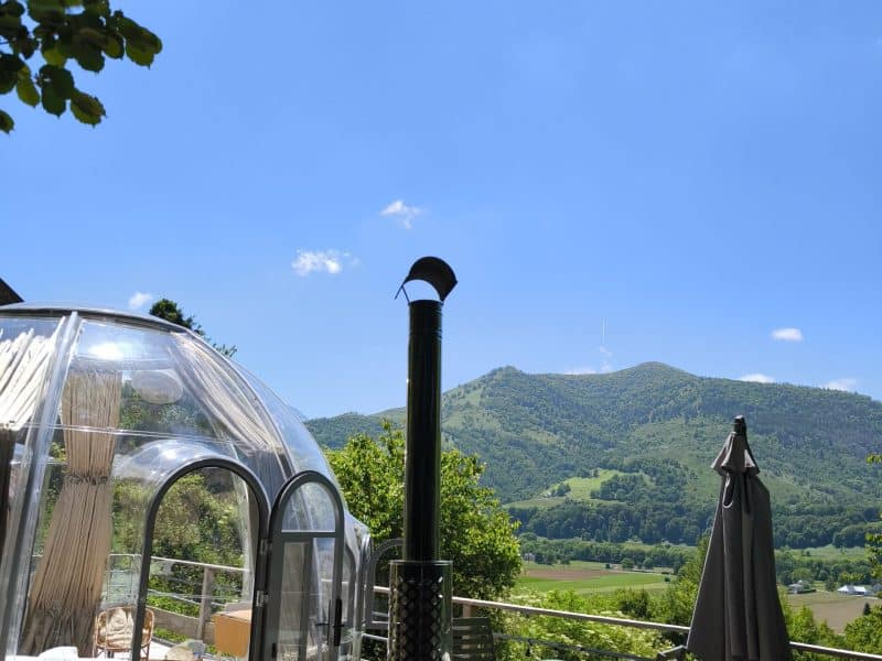 Dôme transparent avec vue sur la montagne, jacuzzi et terrasse ensoleillée. Évasion unique !