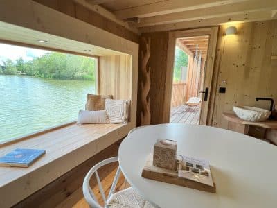 Cabane en bois au bord de l'eau, avec une vue panoramique et un coin salon lumineux.