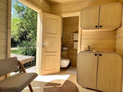 Cabane en bois lumineuse avec intérieur en pin, offrant une vue sur la nature verdoyante.