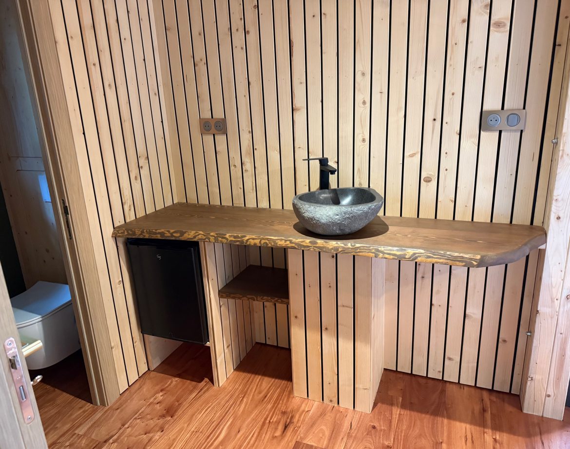 Salle de bain en bois avec lavabo en pierre, dans un hébergement insolite chaleureux.