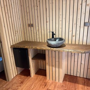 Salle de bain en bois avec lavabo en pierre, dans un hébergement insolite chaleureux.