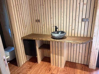 Salle de bain en bois avec lavabo en pierre, dans un hébergement insolite chaleureux.