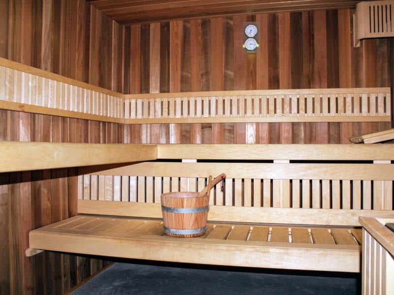Sauna en bois chaleureux avec bancs en bois et seau en bois pour une détente optimale.