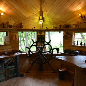 Intérieur chaleureux d'une cabane en bois, avec un grand bar et des fenêtres donnant sur la nature.