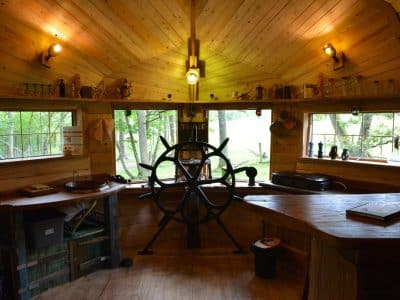 Intérieur chaleureux d'une cabane en bois, avec un grand bar et des fenêtres donnant sur la nature.