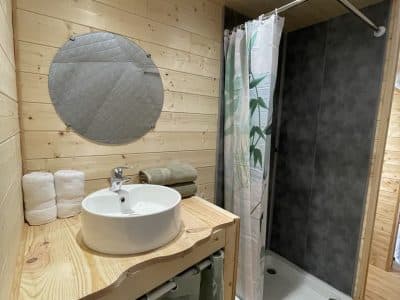 Salle de bain en bois dans un hébergement insolite, avec douche moderne et décor naturel.