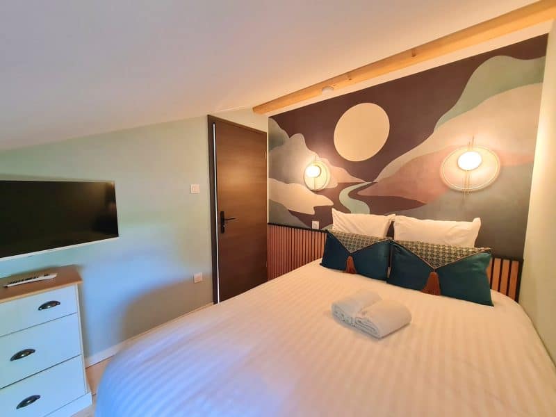 Chambre dhôtes moderne avec lit douillet et mur décoratif apaisant.