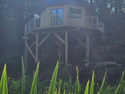Cabane sur pilotis entourée de verdure, offrant une vue imprenable sur la nature environnante.