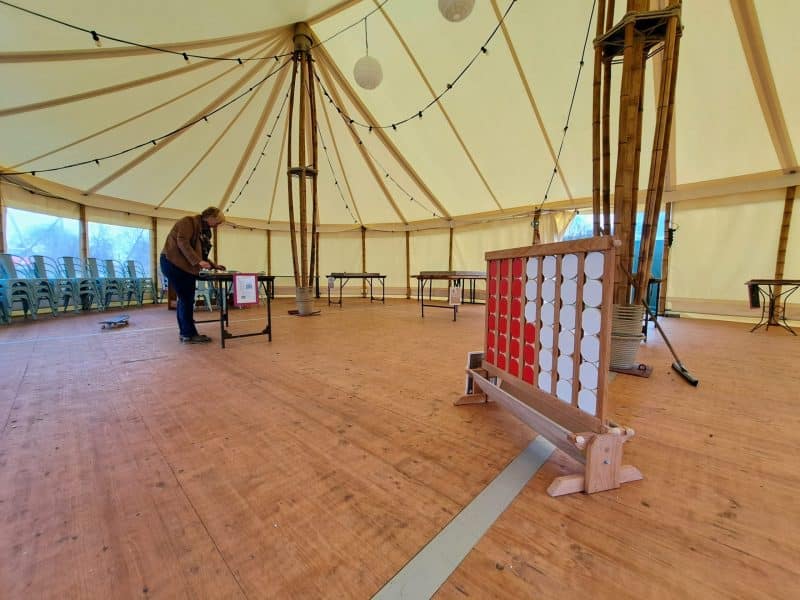 Tente spacieuse avec tables, idéale pour événements, éclairage chaleureux et ambiance conviviale.