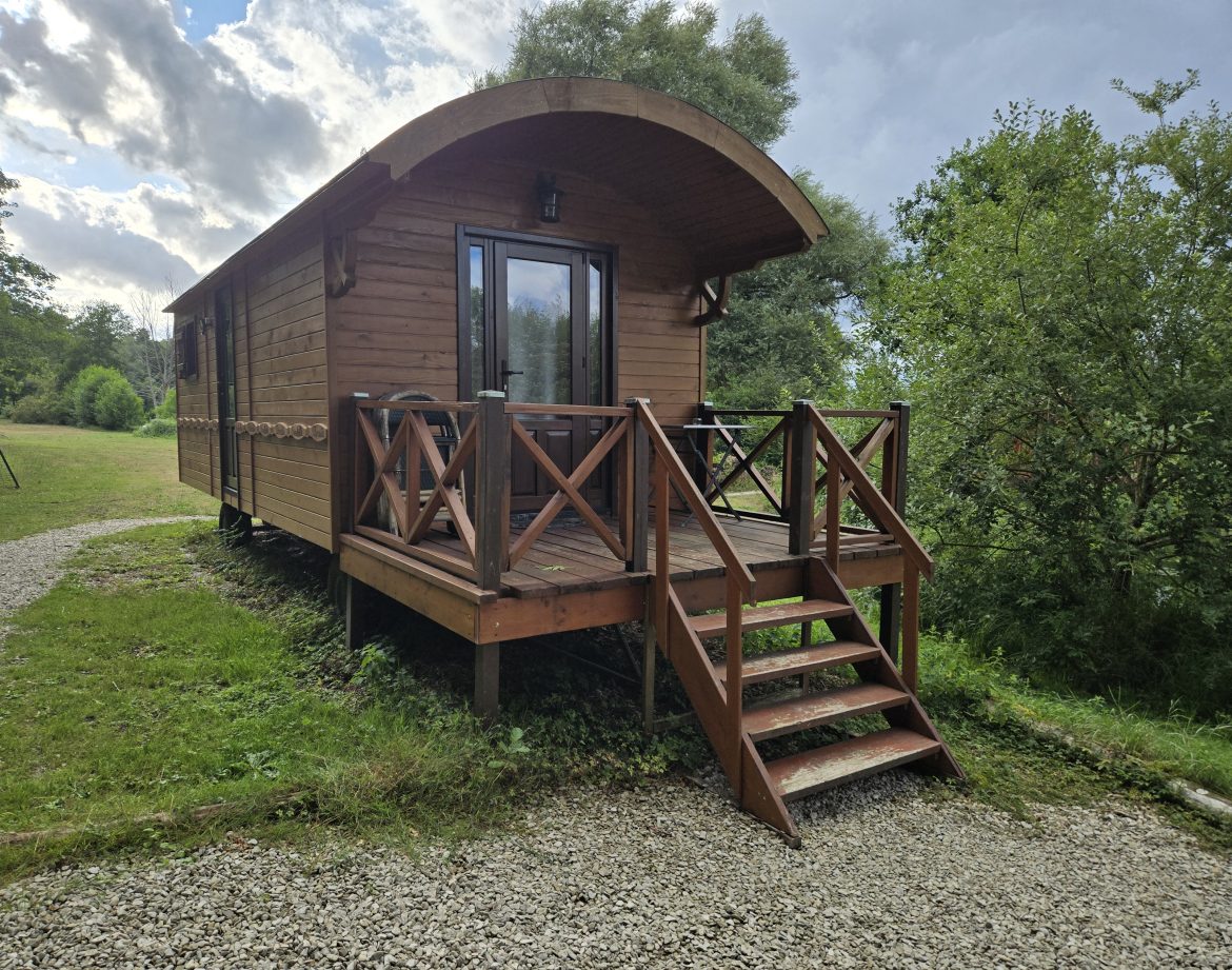 Charmante cabane en bois sur pilotis, avec terrasse en bois et vue sur la nature environnante.