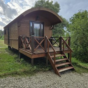 Charmante cabane en bois sur pilotis, avec terrasse en bois et vue sur la nature environnante.