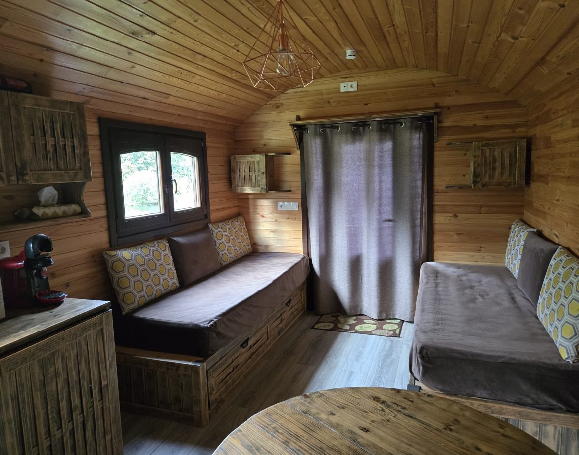 Intérieur d'une cabane en bois, avec canapés confortables et ambiance chaleureuse.
