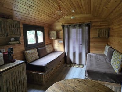 Intérieur d'une cabane en bois, avec canapés confortables et ambiance chaleureuse.