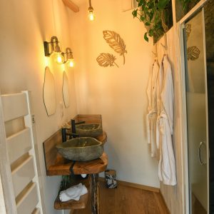 Salle de bain moderne dans un hébergement insolite, avec vasques en pierre et éclairage chaleureux.