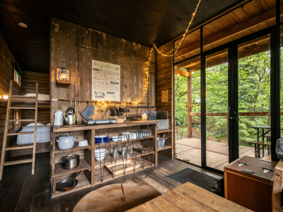 Cabane en bois cosy avec cuisine équipée et vue sur la nature, ambiance chaleureuse.