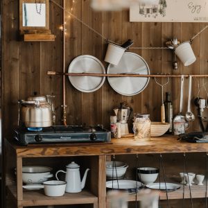 Cuisine chaleureuse d'un hébergement insolite, avec bois brut et vaisselle suspendue.