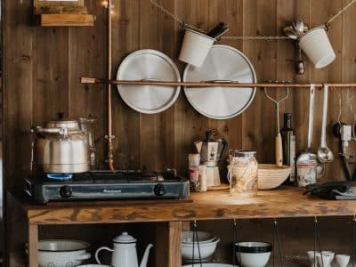 Cuisine chaleureuse d'un hébergement insolite, avec bois brut et vaisselle suspendue.