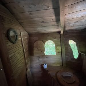 Cabane en bois avec fenêtres arrondies, ambiance chaleureuse et naturelle.