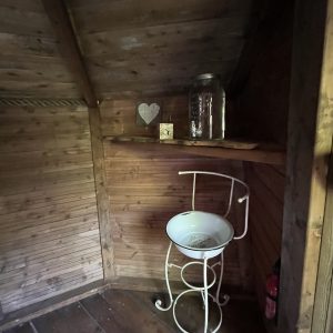 Cabane en bois rustique avec étagère, décorée d'un cœur et d'un jarre en verre.