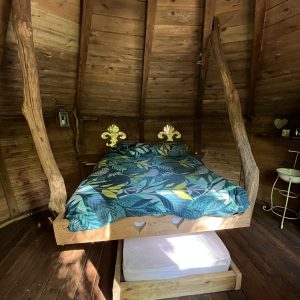 Chambre en forme de cabane avec un lit suspendu et un décor en bois chaleureux.