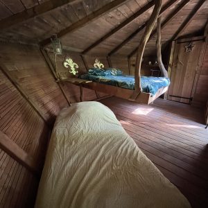 Chalet en bois avec lit suspendu et décoration artisanale, ambiance chaleureuse et cosy.