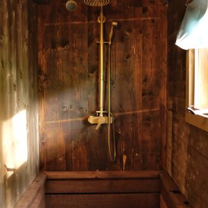 Douche en bois dans un hébergement insolite, ambiance chaleureuse et naturelle.