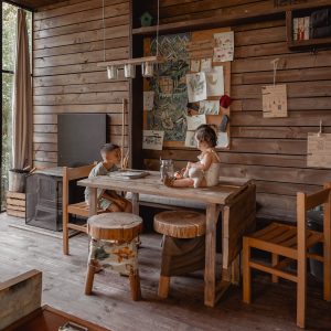 Intérieur chaleureux d'un chalet en bois, avec une table en bois et des enfants jouant.