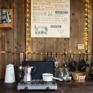 Cabane en bois avec une cuisine rustique, éclairée par des guirlandes lumineuses.