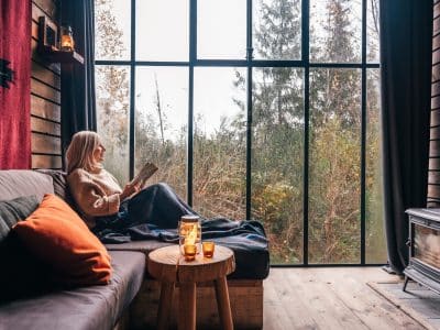 Un chalet moderne avec de grandes fenêtres, offrant une vue sur la nature, idéal pour se détendre.