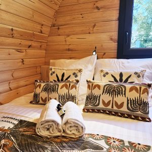 Cabane en bois chaleureuse avec literie élégante et coussins décoratifs. Ambiance cocooning.