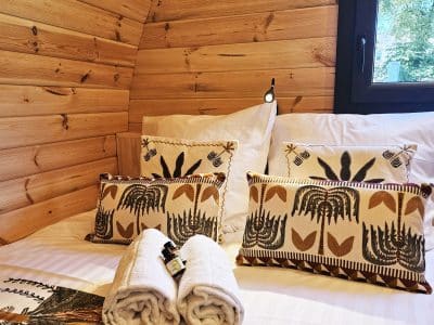 Cabane en bois chaleureuse avec literie élégante et coussins décoratifs. Ambiance cocooning.