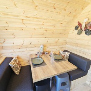 Intérieur chaleureux d'un chalet en bois, avec table en bois et banquettes confortables.