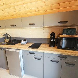 Cuisine moderne et fonctionnelle dans un hébergement insolite en bois, avec équipements récents.