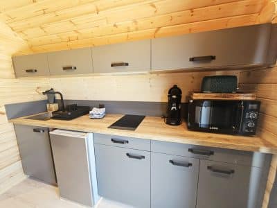 Cuisine moderne et fonctionnelle dans un hébergement insolite en bois, avec équipements récents.