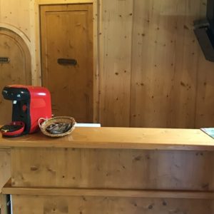 Intérieur chaleureux d'un hébergement insolite en bois, avec une machine à café rouge et des portes