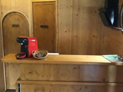 Intérieur chaleureux d'un hébergement insolite en bois, avec une machine à café rouge et des portes