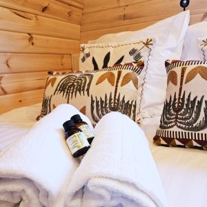 Chalet en bois chaleureux avec literie douillette et serviettes blanches, ambiance nature.