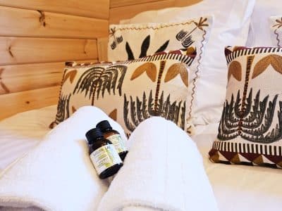 Chalet en bois chaleureux avec literie douillette et serviettes blanches, ambiance nature.