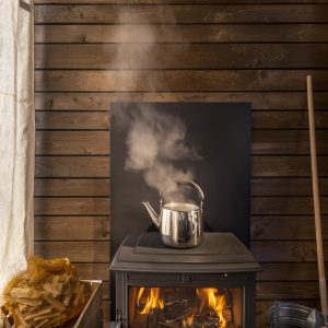 Chalet chaleureux avec un poêle à bois, bouilloire fumante et ambiance cocooning.