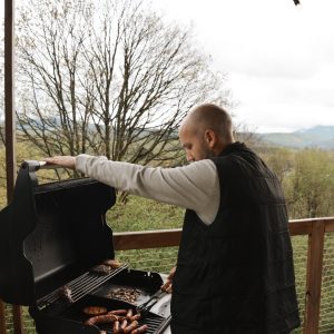 Un chalet en bois avec vue sur la nature, barbecue en cours sur la terrasse.