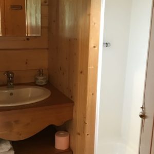Salle de bain en bois dans un hébergement insolite, avec lavabo et douche moderne.