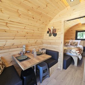 Intérieur chaleureux d'un hébergement insolite en bois, avec coin repas et lit douillet.