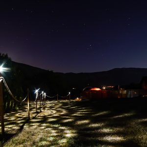 Hébergement insolite sous les étoiles, avec un chemin lumineux menant à des structures uniques.