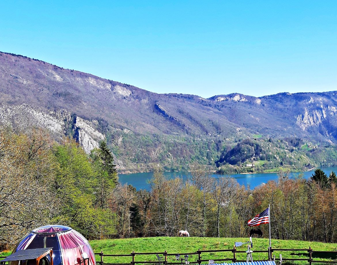 Dôme transparent en pleine nature, avec vue imprenable sur le lac et les montagnes environnantes.