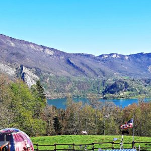 Dôme transparent en pleine nature, avec vue imprenable sur le lac et les montagnes environnantes.